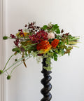 Bouquet of flowers in a black vase against a white wall