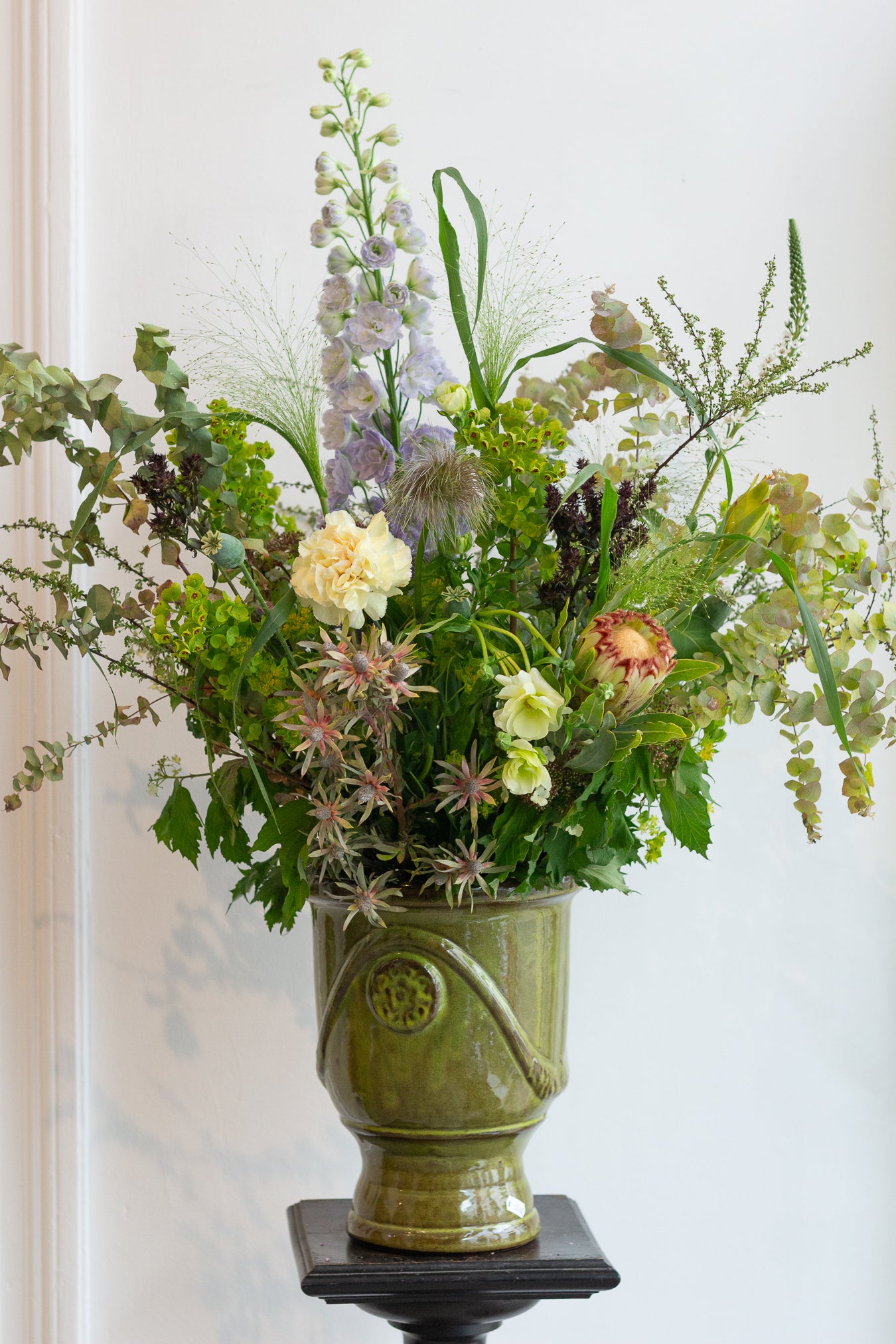 Floral arrangement in a green ceramic vase on a white background