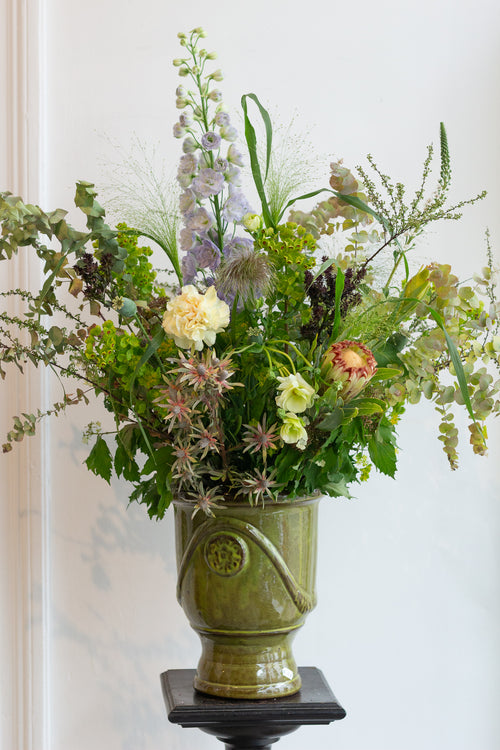 Floral arrangement in a green ceramic vase on a white background