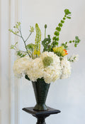 Floral arrangement in a dark green vase on a white background