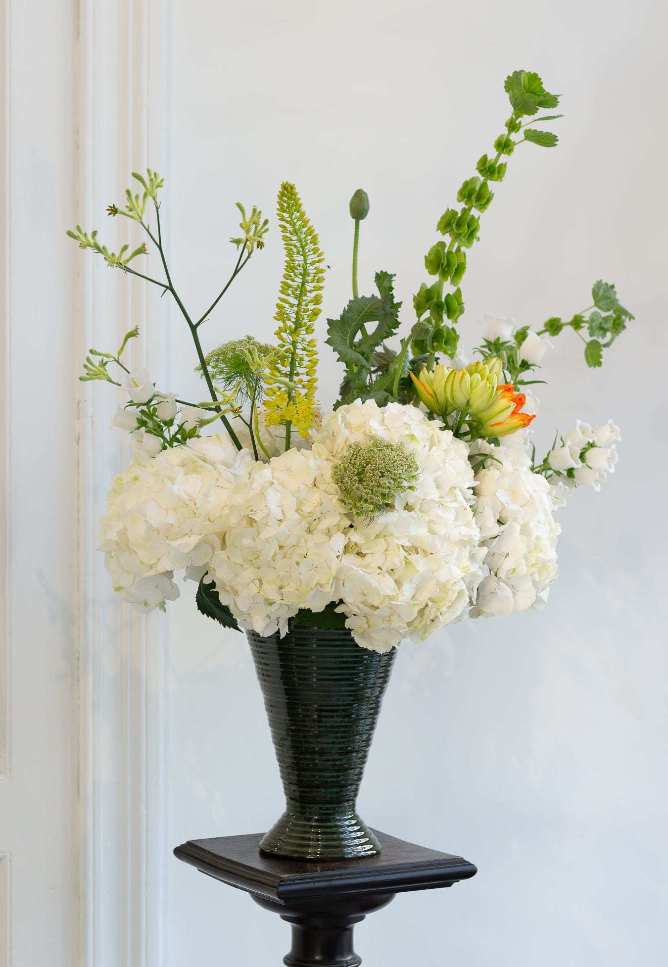 Floral arrangement in a dark green vase on a white background