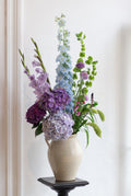 Vase with colorful flowers on a stand against a white wall