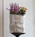 White paper bag with flowers against a white wall