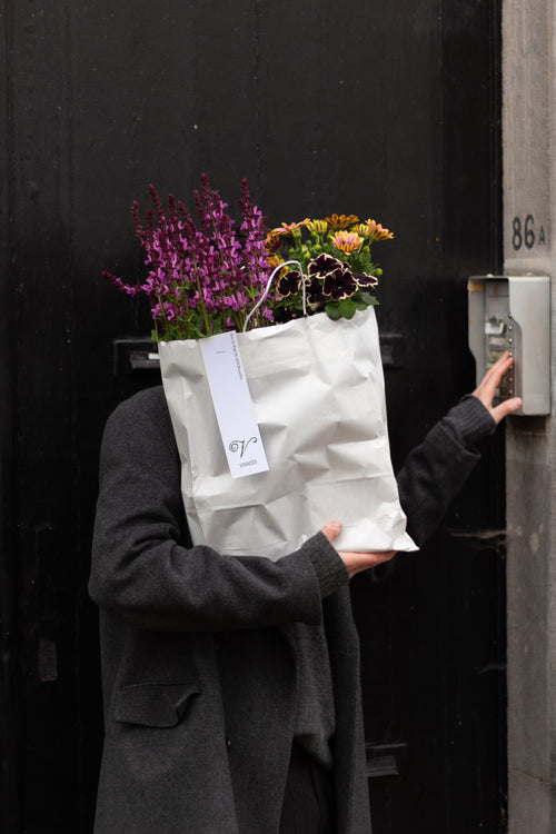 Person holding a bag of flowers against a dark background
