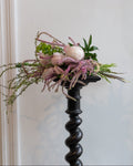Floral arrangement on a decorative black pedestal against a white wall