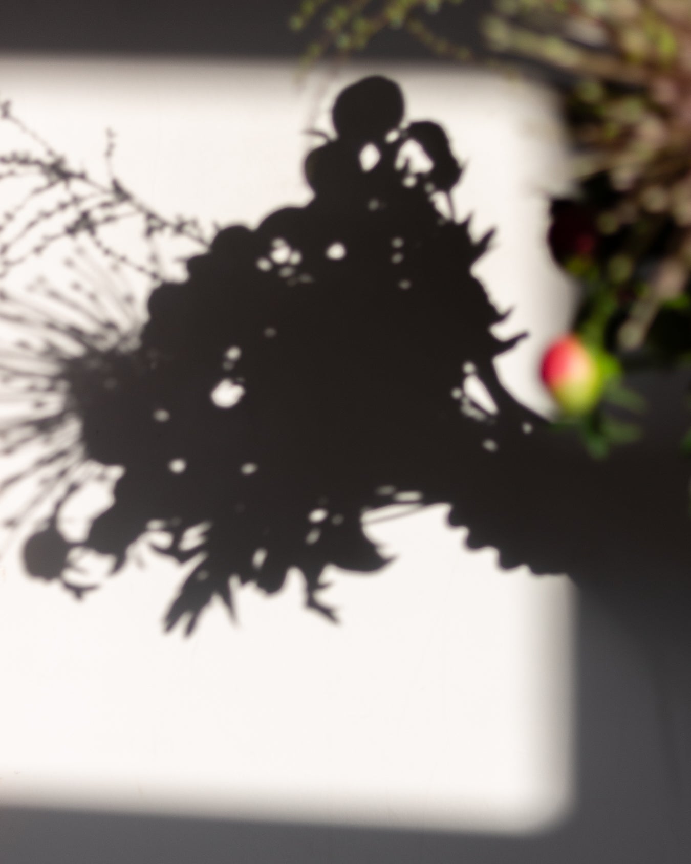 Blurred image of a decorative wreath with a silhouette of a couple and a red berry.